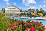 A view of the resort-style pool surrounded by colorful flowers and lounge chairs in a gated apartment community in Hammond.