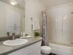 Stylish apartment bathroom featuring a modern sink, mirror, and shower area with light decor
