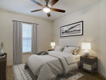 Modern bedroom featuring a ceiling fan, stylish decor, and cozy bedding in a well-lit apartment.