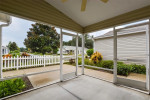 Screened lanai view of a beautiful patio villa in The Villages, FL, showcasing lush greenery and a white picket fence.