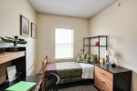 Furnished bedroom in an apartment at 59 Broad St, Plattsburgh, featuring a bed, desk, and decor.