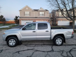 2010 Toyota Tacoma SR5 TRD Sport Quad Cab 4x4 in silver, showing side view on a residential street.