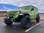 2018 Jeep Wrangler Rubicon in bright green, parked with off-road tires and winch, showcasing its rugged design.