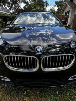 Front view of a 2016 BMW 5 Series in black with reflections on the hood, showcasing its sleek design.