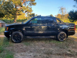 2007 Chevrolet Avalanche with blacked-out wheels, parked outdoors in natural setting