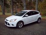2013 Ford Focus SE Hatchback in white parked among trees, showcasing its clean condition and modern design.