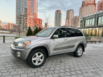 2001 Toyota RAV4 SUV with leather seats and roof rack, parked in urban setting.