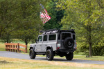 1993 Land Rover Defender 110 in Nardo Grey parked in a scenic outdoor setting.
