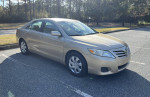 2011 Toyota Camry in gold color parked, features low mileage and clean CARFAX report.
