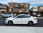 2019 Kia Optima LX sedan in pearl white, 76K miles, parked on the street with residential background.