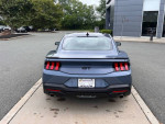 Rear view of a 2024 Ford Mustang GT Premium in a parking lot, showcasing its sleek design and 3,932 miles.