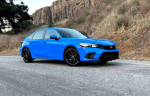 2024 Honda Civic Sport hatchback in blue color parked on a gravel road with rocky hills in the background