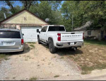 2024 Chevrolet Silverado 2500HD LT parked in front of a house, showcasing its good condition and affordability.