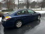 2010 Nissan Altima 2.5 SL Sedan parked on a rainy driveway, showcasing its sleek design and shiny alloy wheels.