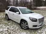 2016 GMC Acadia Denali FWD parked in a snowy yard, showcasing its modern design and premium features.