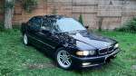 2001 BMW 740iL in black parked on the grass, showcasing its sleek design and well-maintained appearance.