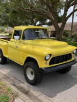 1955 Chevy 3100 4x4 yellow truck with minimal rust, parked on the street, showcasing its classic design.