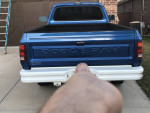 Rear view of a blue 1991 Dodge D250 truck parked outside, showcasing original paint and design features.