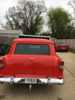 Rear view of a restored 1955 Chevy Sedan Delivery in vibrant red, showcasing chrome details and new features.