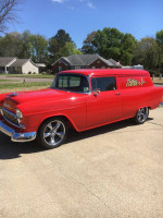 1955 Chevy Sedan Delivery in red with custom wheels parked outdoors under blue sky