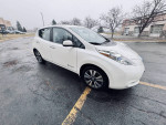2013 Nissan Leaf SL parked on a wet road, ideal eco-friendly car for students, spacious and reliable.