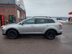 2010 Mazda CX-9 Grand Touring FWD in gray, parked at a gas station with winter scenery.