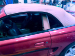 Interior view of a 1995 Ford Mustang GT convertible with black leather seats and beige soft top.