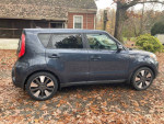 Side view of a 2016 Kia Soul in good condition with 134,000 miles, parked on a leaf-covered ground.