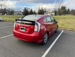 Red 2012 Toyota Prius Five parked, in excellent condition, showcasing its hatchback design and winter tires.