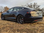 2014 Tesla Model S 85 in great condition, showcasing rear profile on grass with trees in background