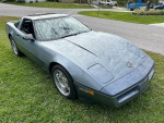 1990 Chevrolet Corvette in Steel Blue Metallic parked on grass, showcasing its classic design and powerful V8 engine.