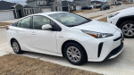 2021 Toyota Prius parked on a driveway, showcasing its sleek design and hybrid technology.