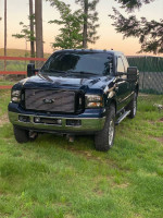 2006 Ford F350 Lariat 4WD truck in blue with some rust, located on grass, ready for trade or sale.