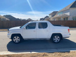 Side view of a 2010 Honda Ridgeline 4WD parked on a street, showcasing its clean design and features.