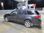 2012 Subaru Outback Limited parked at a gas station, showing its sleek design and winter tires.