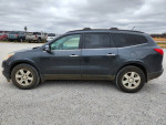 2011 Chevrolet Traverse in gray parked on gravel with a cloudy sky