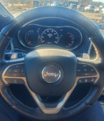 Interior view of a 2015 Jeep Cherokee Sport FWD dashboard with steering wheel and gauges.
