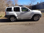 2009 Nissan Xterra 4x4 in white, featuring clean lines and off-road capabilities, parked on a rural road.