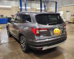2019 Honda Pilot Touring in blue-grey with black leather interior, parked in a service area.