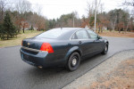 2014 Chevrolet Caprice PPV police package in dark color parked on a street with trees and houses in background.