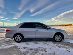 2005 Honda Accord LX Sedan exterior side view on snowy ground, showcasing its clean lines and sleek design.