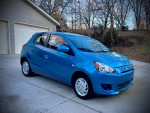 2015 Mitsubishi Mirage in blue, low mileage, parked on concrete near a garage, showing slight hail damage.