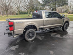2023 Ford F250 Super Duty Crew Cab in beige with black appearance package, parked outdoors.