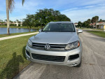 Front view of a silver Volkswagen SUV parked on a residential street near a lake, showcasing its low mileage and great condition.