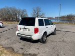 2005 Honda Pilot 4WD in white parked by a lake with trees in the background, featuring third-row seating.