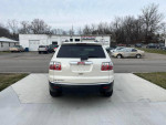 Rear view of a 2010 GMC Acadia, pearl white SUV parked outside with a clean design and minimal background distractions.