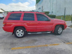 Red 2001 Jeep Grand Cherokee Limited SUV parked, showcasing leather interior and power moonroof.
