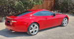 2014 Jaguar XKR Coupe in red, showcasing its sleek design and sporty features, parked in a scenic outdoor setting.