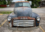 Front view of a vintage 1950 GMC 100 truck needing restoration, with visible wear and a rustic appearance.