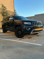 2015 Jeep Grand Cherokee Limited FWD in great condition parked outside with a blue sky background.